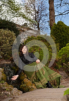 Woman in Victorian fashion with hand in waterfall in park