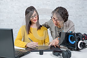Woman video editor and young assistant using graphic tablet