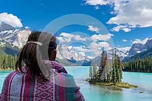 Woman views Spirit Island from the shoreline of Maligne Lake in Jasper National Park