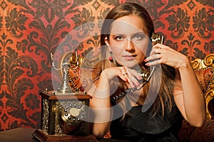 Woman on vintage chair and talking on old phone