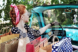 Woman in vintage clothes is driving old car after shopping.