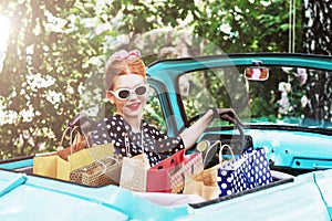 Woman in vintage clothes is driving old car after shopping.