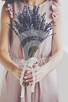 Woman in vintage dress holding bunch of lavender in her hands