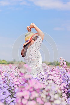 A woman in a vintage dress stretch oneself out in Purple flower field in the morning after waking up. Young tourists strolling