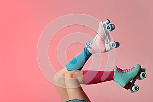 Woman with vintage roller skates on color background