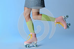 Woman with vintage roller skates on color background