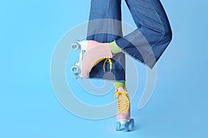 Woman with vintage roller skates on color background