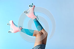 Woman with vintage roller skates on color background