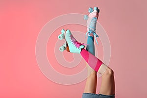 Woman with vintage roller skates on color background