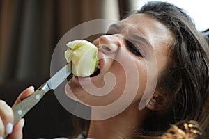 The woman violently bites an Apple with a knife.