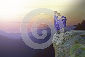 Woman in violet dress on cliff