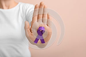 Woman with violet ribbon on color background, closeup. Domestic violence concept