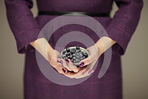Woman in violett 50`s dress hands holding some blueberries