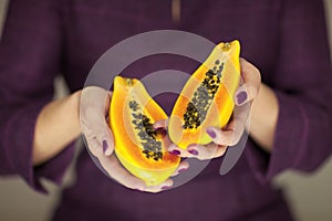 Woman in violett 50`s dress hands holding some papayas