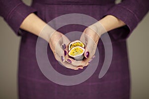 Woman in violett 50`s dress hands holding some passion fruits