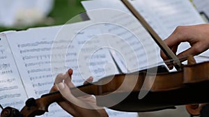 Woman violin musician playing by notes outdoor. Lovely young woman is playing musical instrument.