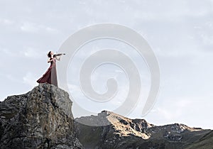 Woman violinist in red dress playing melody against cloudy sky