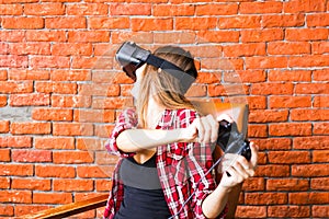 Woman in virtual reality headset or 3d glasses and headphones playing video game with controller gamepad