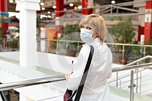 A woman in a virus mask walks around a public place in the city