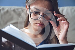 A woman with vision problems is reading a book with glasses