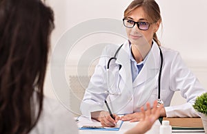 Woman Visiting Female Physician Sitting In Clinic Office