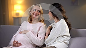 Woman visiting her pregnant friend at home, happy motherhood, baby waiting