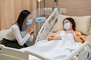 Woman visiting and take care female patient on bed at hospital. people must be wearing medical mask to prevention coronavirus