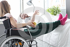 Woman visitor sitting in wheelchair near patient in bed