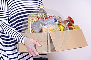 Woman volunteer hands holding food donations box with food grocery products