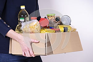 Woman volunteer hands holding food donations box with food grocery products