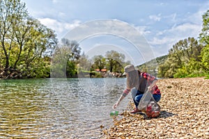 Woman volunteer helps clean the shore of river of garbage. Earth day and environmental improvement concept