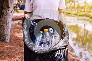 Woman volunteer holding black color garbage bag with plasatic bottle at park,Dispose recycle and waste management concept,Close up