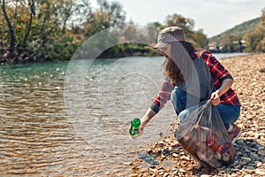 A woman volunteer pulls a bottle out of the water, during the event to clean the river Bank. Earth day and environmental