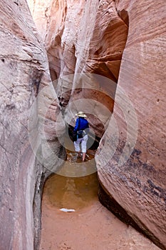 Woman wading though water in slot canyon.