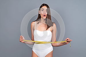 Woman waist with tape, weight loss. Female model body care. Woman holding the meter with hands and measuring waist.