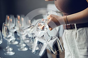 Woman waiter takes few empty wine glasses from bar table, close up without face. Restaurant service and staff serving.