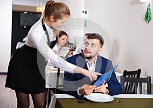 Woman waiter is taking order from client in restaurante