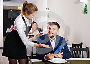 Woman waiter is taking order from client in restaurante