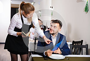 Woman waiter is taking order from client in restaurante