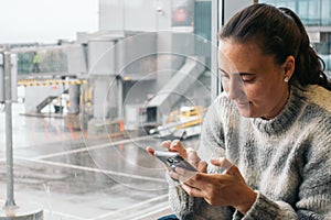 Woman waiting at the airport using her smartphone