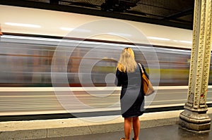 Woman waiting in front of moving subway train