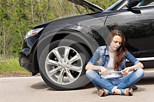 Woman waiting beside her broken down car