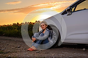 Woman waiting beside her car on a rural road