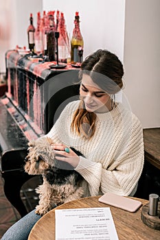 Woman waiting for her order in cafe with her dog