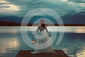 Woman waiting with lantern on a pier photo