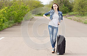 Woman waiting in the road with her suitcase