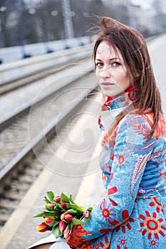 Woman waiting train with flowers at hand