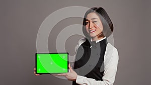 Woman waitress holding tablet with greenscreen display on camera