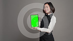 Woman waitress holding tablet with greenscreen display on camera