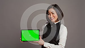 Woman waitress holding tablet with greenscreen display on camera